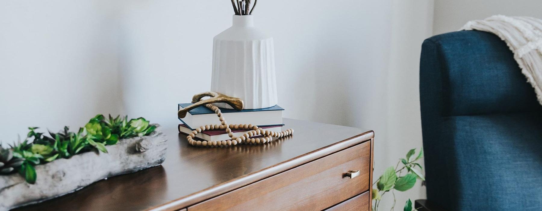 a dresser with a vase of plants on top