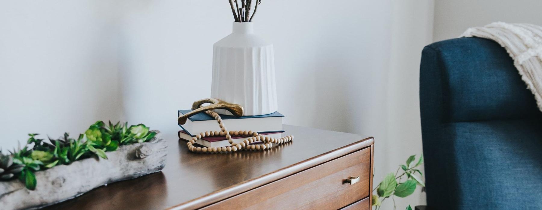 a dresser with a vase of plants on top